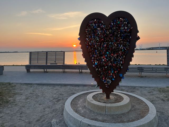 Ein Herz aus Metall voller Liebesschlösser bei Sonnenuntergang am Yachthafen von Fehmarn